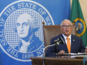 Washington Gov. Jay Inslee glances at an aide holding up an image of a visual slide being shown to viewers of a news conference, Thursday, June 3, 2021, in Olympia, Wash. Inslee announced that Washington will be the latest state to offer prizes to encourage people to get vaccinated against COVID-19. Incentives will include a series of giveaways during the month of June including lottery prizes totaling $2 million, college tuition assistance, airline tickets, and game systems. (AP Photo/Ted S.