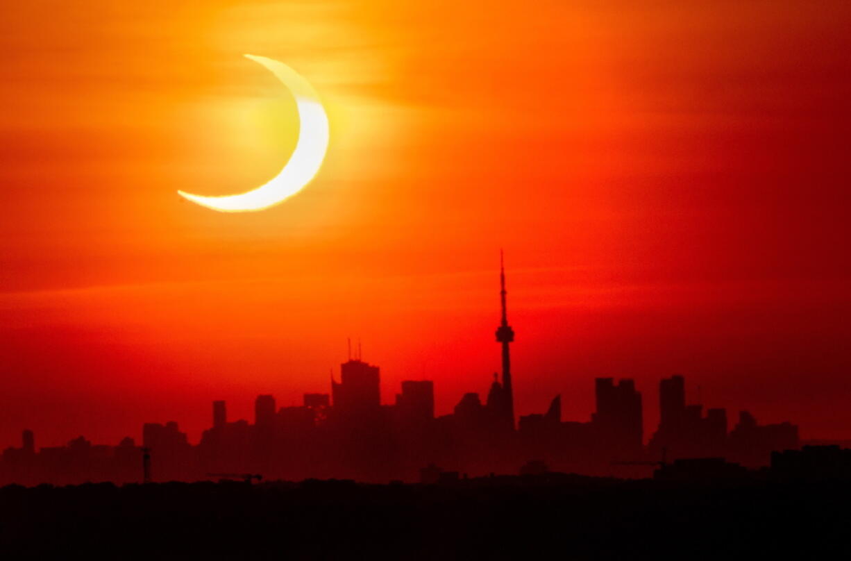 An annular solar eclipse rises over the skyline of Toronto on Thursday, June 10, 2021.