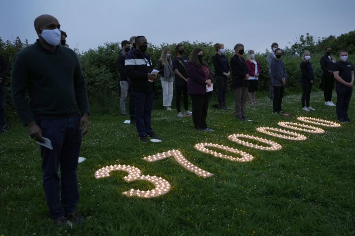 Campaigners attend a vigil to remember the millions who have died during the COVID-19 pandemic, organised by 'Crack the Crisis Coalition' in Falmouth, Cornwall, England, Friday, June 11, 2021. Leaders of the G7 began their first of three days of meetings on Friday in Carbis Bay, in which they will discuss COVID-19, climate, foreign policy and the economy.