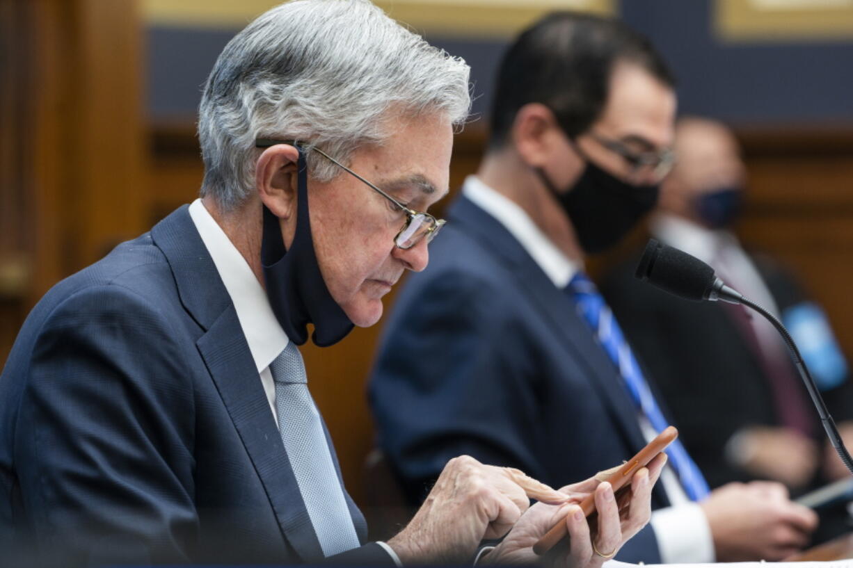 FILE - In this Dec. 2, 2020 file photo, Federal Reserve Chair Jerome Powell, left, arrives to testify before a House Financial Services Committee hearing on Capitol Hill in Washington.  Powell says, Friday, June 4, 2021,  the U.S. central bank is studying how climate change might affect banks. But the Fed doesn't see itself as getting involved in how to fight climate change.