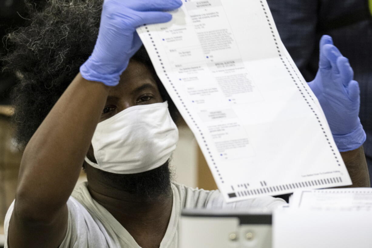 FILE - In this Nov. 25, 2020 file photo, workers scan ballots as the Fulton County presidential recount gets under way  at the Georgia World Congress Center in Atlanta. Reports from an independent monitor who observed election operations in Georgia's most populous county during the 2020 election cycle detail tense encounters with party election monitors.