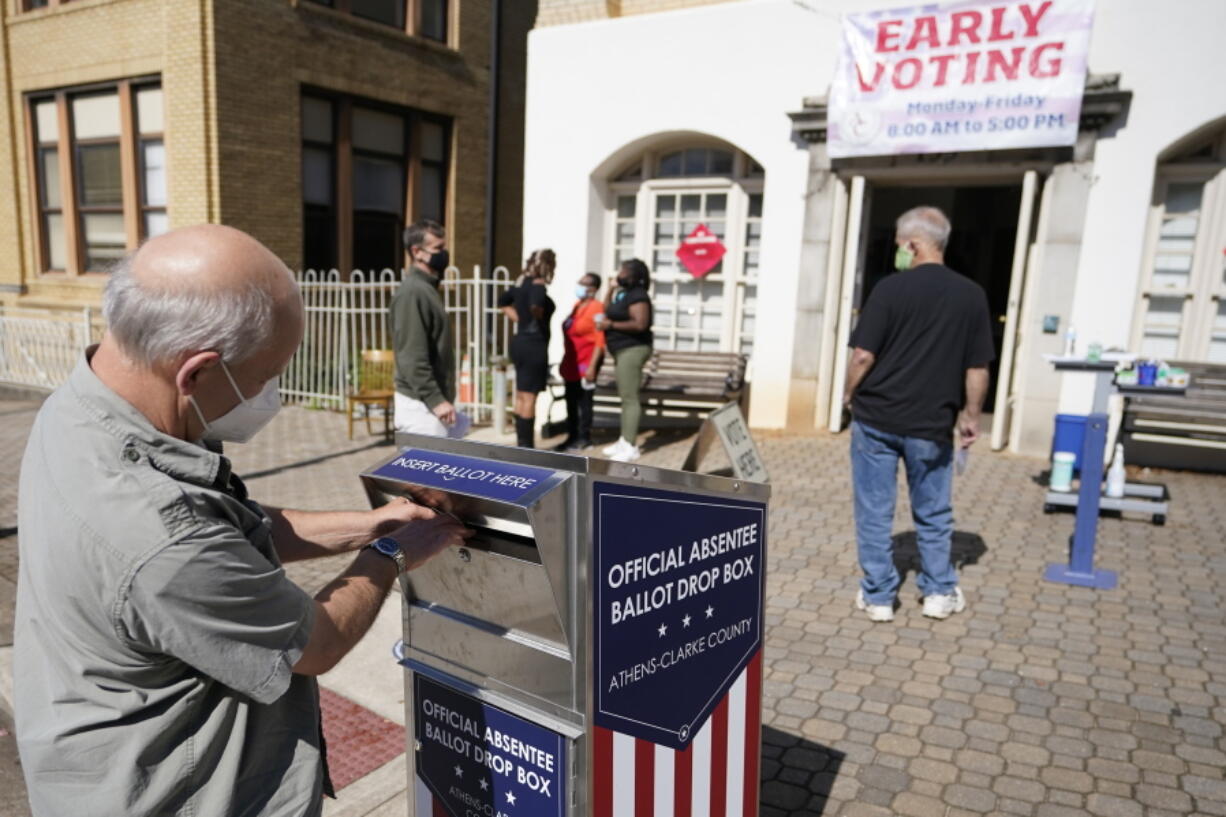 FILE - In this Monday, Oct. 19, 2020 file photo, a voter submits a ballot in an official drop box during early voting in Athens, Ga.