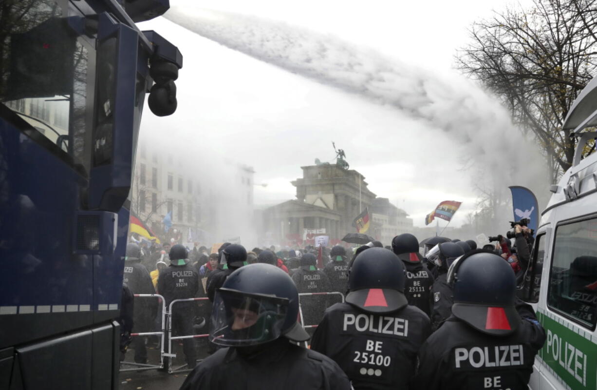 File - In this Wednesday, Nov. 18, 2020 file photo, police uses water canons to clear a blocked a road between the Brandenburg Gate and the Reichstag building, home of the German federal parliament, as people attend a protest rally in Berlin, Germany, against the coronavirus restrictions in Germany. Authorities in Germany say the number of far-right extremists in the country increased last year as neo-Nazis sought to join protests against pandemic-related restrictions. German Interior Minister Horst Seehofer said authorities counted 33,300 far-right extremists in 2020, an increase of almost 4% from the previous year.