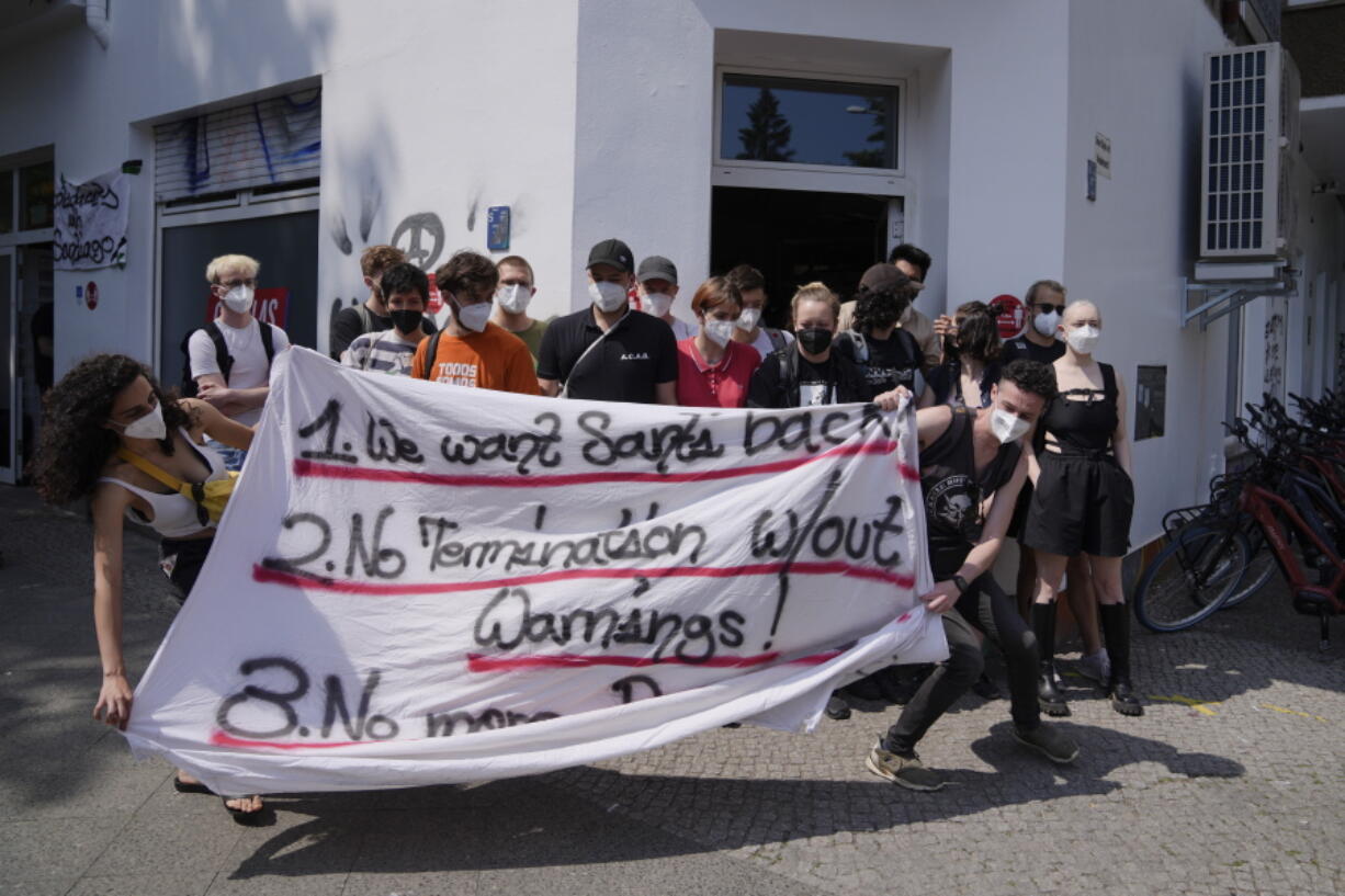 Zeynep, left, a Gorillas rider from Turkey who declined to give her last name for fear of facing repercussions from the company, blocks with other workers the entrance of a depot for German startup Gorillas, a grocery delivery company, to protest the firing of a colleague in Berlin, Germany, Thursday, June 10, 2021. The company Gorillas operates in dozens of cities across Germany, France, Italy, the Netherlands and Britain, and has already set its sights on New York.