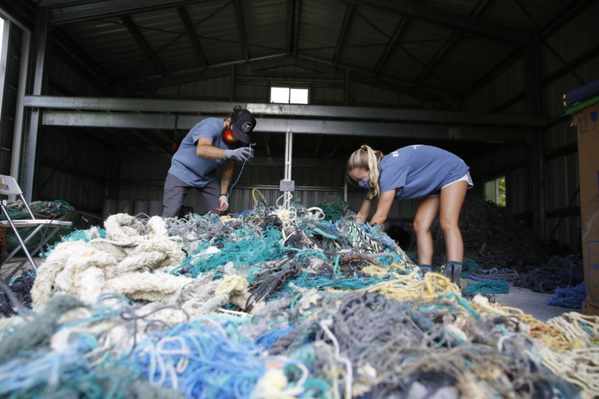 Hawaii Pacific University graduate student Drew McWhirter, left, and Raquel Corniuk, a research technician at the university's Center for Marine Debris Research, pull apart a massive entanglement of ghost nets May 12 in Kaneohe, Hawaii. The two are part of a study that is attempting to trace derelict fishing gear that washes ashore in Hawaii back to the manufacturers and fisheries that it came from.