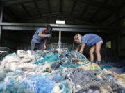 Hawaii Pacific University graduate student Drew McWhirter, left, and Raquel Corniuk, a research technician at the university's Center for Marine Debris Research, pull apart a massive entanglement of ghost nets May 12 in Kaneohe, Hawaii. The two are part of a study that is attempting to trace derelict fishing gear that washes ashore in Hawaii back to the manufacturers and fisheries that it came from.