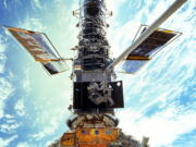 FILE - In this image provided by NASA/JSC, astronauts Steven L. Smith and John M. Grunsfeld are photographed during an extravehicular activity (EVA) during the December 1999 Hubble servicing mission of STS-103, flown by Discovery. The Hubble Space Telescope has been blindsided by computer trouble, with all astronomical viewing halted, NASA said Wednesday, June 16, 2021. The orbiting observatory has been idle since Sunday when a 1980s-era computer that controls the science instruments shut down, possibly because of a bad memory board.