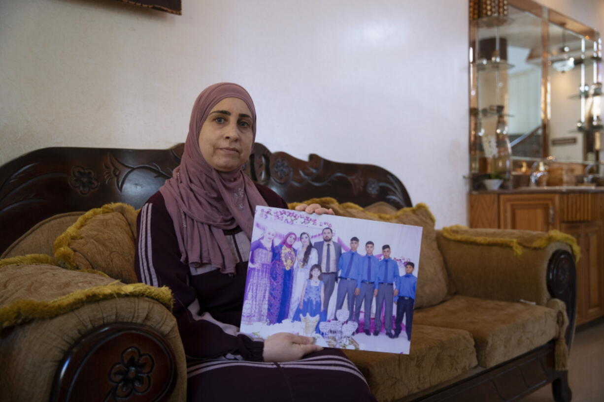 Sanaa Shalaby, displays a picture of her estranged husband, Muntasser Shalaby, center, who Israeli security forces accuse of carrying out a May 2 shooting that killed an Israeli and wounded two others in the occupied West Bank, at her home in the West Bank village of Turmus Ayya, Thursday, June 3, 2021. Shalaby is waging a legal battle to prevent Israel from demolishing the two-story villa where she lives with her three youngest children that's drawing attention to Israel's policy of punitive home demolitions, which rights groups view as collective punishment.