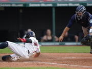 Cleveland Indians' Cesar Hernandez, left, scores as Seattle Mariners catcher Tom Murphy is late on the tag in the 10th inning of a baseball game, Saturday, June 12, 2021, in Cleveland.