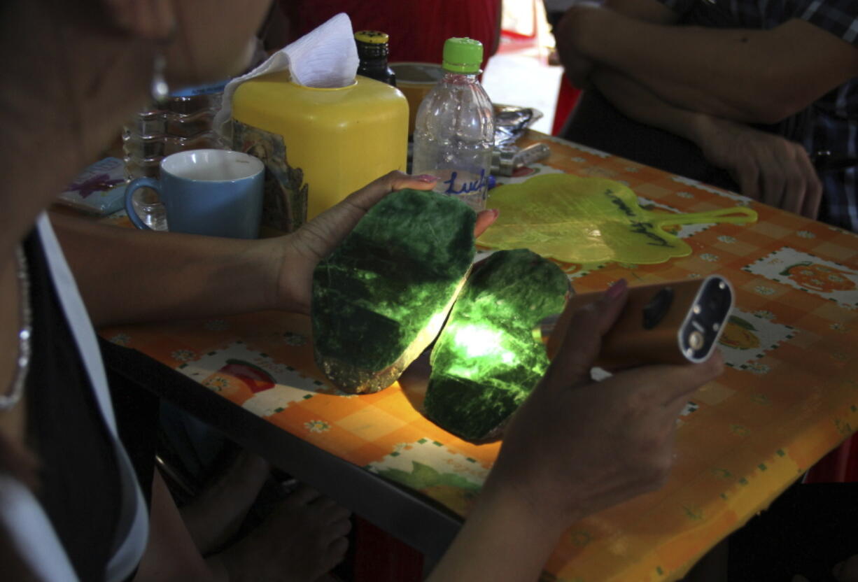 FILE - In this Sept. 18, 2015, file photo, local people examine the quality of a jade stone in the Hpakant area of Kachin state, northern Myanmar. A report by the independent research group Global Witness says Myanmar's Feb. 1 military takeover has crushed prospects for better safety and environmental controls in its lucrative but conflict-ridden jade mining sector.