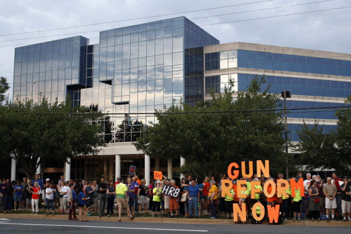 FILE - In this Aug. 5, 2019, file photo, people gather at a vigil for recent victims of gun violence outside the National Rifle Association's headquarters building in Fairfax, Va. The NRA has been embroiled in a legal and financial battle that liberals have cheered as the potential downfall of the powerful gun rights lobby, opening up a wide path for reform. Not so fast. While the battle over gun rights is shifting from Washington to the states, the NRA's message has become so solidified in the Republican political fabric that it's self-sustaining, even if the gun rights organization that led the way ceases to exist, leaders on both sides say.