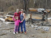 In this photo provided by Tye and Melynda Small, they are seen standing with their 5-year-old daughter, Madalyn, in front of the ruins of their home in Otis, Oregon after the Echo Mountain Fire swept through, burning nearly 300 homes, in September, 2020. The Smalls had to take Madalyn back to their property to help her understand why they couldn't go home. Oregon's unprecedented wildfire season last fall burned 4,000 homes and more than 1 million acres in areas that aren't normally associated with wildfire. Experts say the 2020 wildfire season in Oregon was a taste of what lies ahead as climate change makes blazes more likely and more destructive even in wetter, cooler climates like the Pacific Northwest.