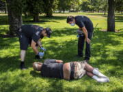 With the temperature well over 100 degrees, Spokane, Wash., firefighter Sean Condon, left and Lt. Gabe Mills, assigned to the Alternative Response Unit of of Station 1, check on the welfare of a man in Mission Park in Spokane, Wash., Tuesday, June 29, 2021. The special fire unit, which responds to low priority calls, has been kept busy during this week's heatwave.