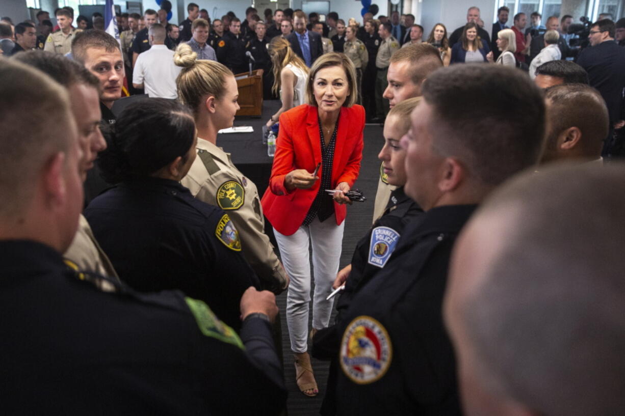 FILE - In this June 17, 2021, file photo, Iowa Gov. Kim Reynolds hands out pens to law enforcement officers after signing the Back the Blue bill, at the Iowa Law Enforcement Academy, in Johnston. Some Republican-controlled states have responded to persistent calls for police reform by moving in the other direction. Reynolds signed a bill to expand qualified immunity for police officers and enhance penalties for protesters, including elevating rioting to a felony.