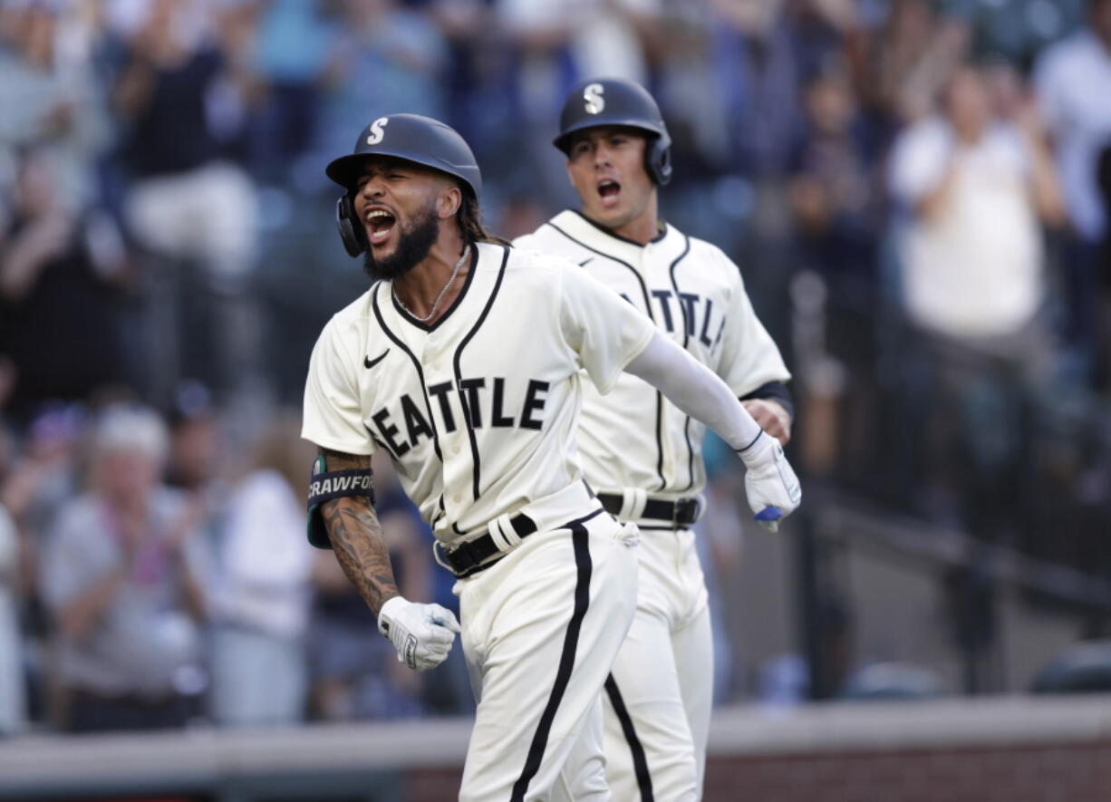 Seattle Mariners' J.P. Crawford celebrates at home with Dylan Moore behind, after hitting a grand slam off Tampa Bay Rays starting pitcher Josh Fleming during the second inning of a baseball game Saturday, June 19, 2021, in Seattle.