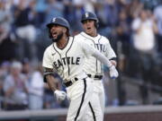 Seattle Mariners' J.P. Crawford celebrates at home with Dylan Moore behind, after hitting a grand slam off Tampa Bay Rays starting pitcher Josh Fleming during the second inning of a baseball game Saturday, June 19, 2021, in Seattle.