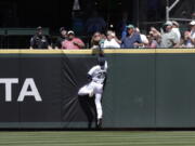 The home run ball hit by Colorado Rockies' Brendan Rodgers bounces among fans in the stands with Seattle Mariners center fielder Taylor Trammell leaping during the second inning of a baseball game, Wednesday, June 23, 2021, in Seattle.