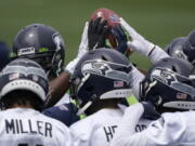 Seattle Seahawks defensive players touch the football during a huddle at NFL football practice Tuesday, June 15, 2021, in Renton, Wash. (AP Photo/Ted S.