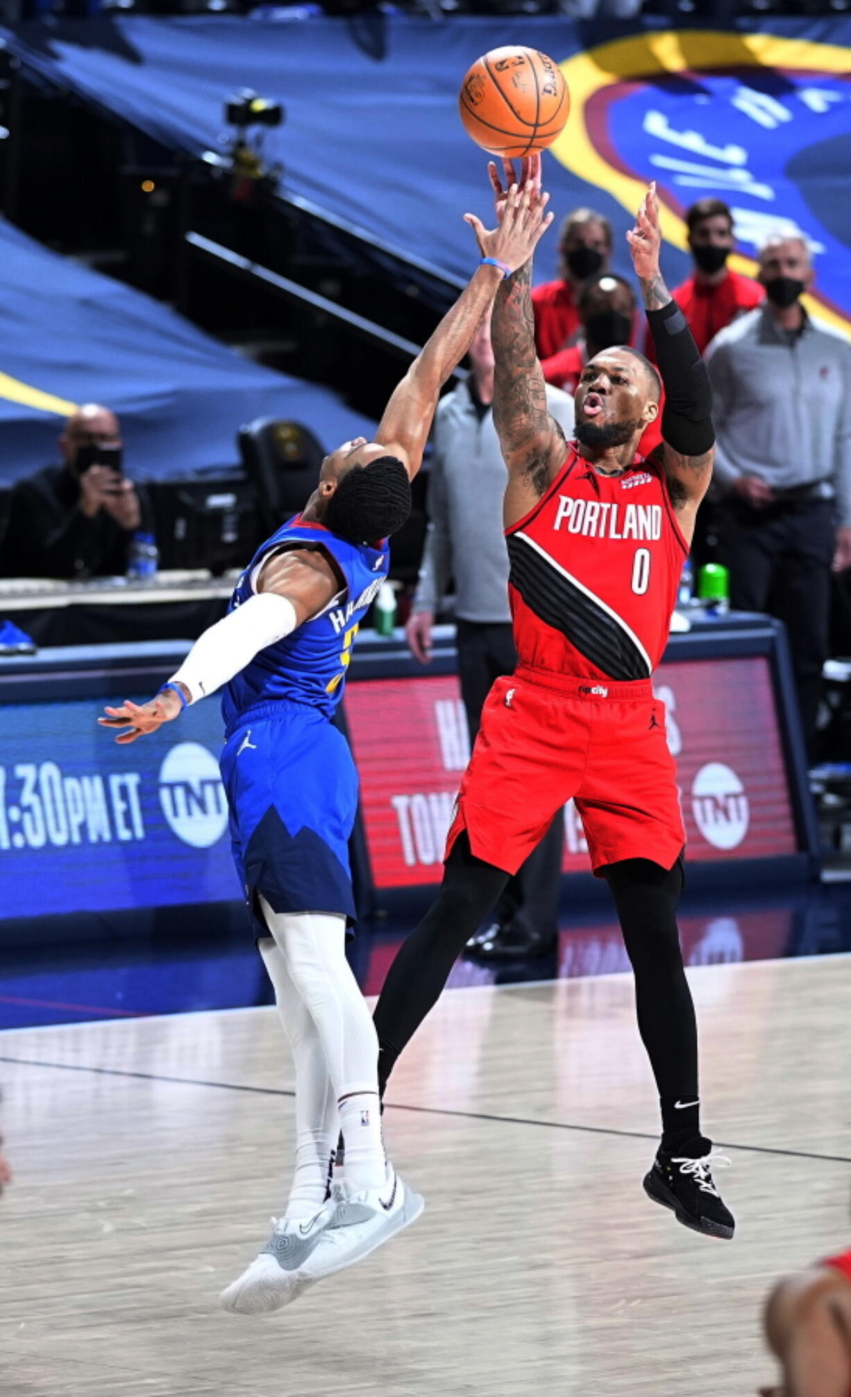 Portland Trail Blazers guard Damian Lillard (0) shoots a 3-point basket against Denver Nuggets guard Shaquille Harrison (3) to send Game 5 of a first-round NBA basketball playoff series into a second overtime, Tuesday, June 1, 2021, in Denver.