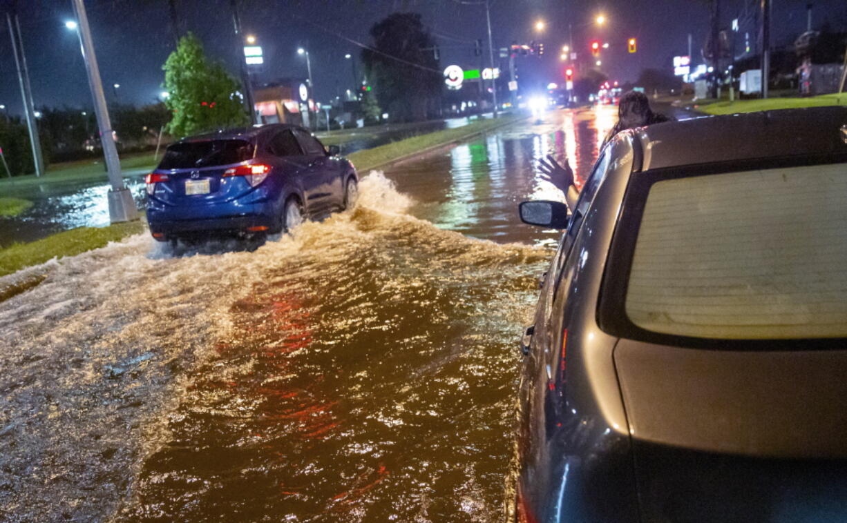 Lamont Pepp, right, waves to a passing motorist to slow down after Pepp's car stalled in high water on Gause Boulevard in Slidell late Friday, June 18, 2021, as a tropical disturbance neared the Louisiana shore. Tropical Storm Claudette has formed Saturday morning along the U.S. Gulf Coast, bringing heavy rains and flooding to coastal states including Louisiana, Mississippi and Alabama.