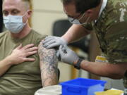 FILE - In this Dec. 16, 2020, file photo, Staff Sgt. Travis Snyder, left, receives the first dose of the Pfizer COVID-19 vaccine given at Madigan Army Medical Center at Joint Base Lewis-McChord in Washington state, south of Seattle. Nurse Jose Picart, right, administered the shot. Washington Gov. Jay Inslee on Thursday, June 17, 2021, announced a new COVID-19 vaccine incentive lottery for the state's military, family members and veterans because the federal government wasn't sharing individual vaccine status of those groups with the state and there were concerns they would be left out of a previously announced lottery. (AP Photo/Ted S.