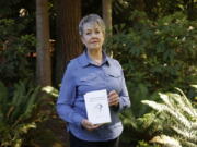 Karen McKnight stands in her backyard on Saturday, June 19, 2021, in Sammamish, Wash., holding two books written by her brother Ross Bagne of Cheyenne, Wyo.