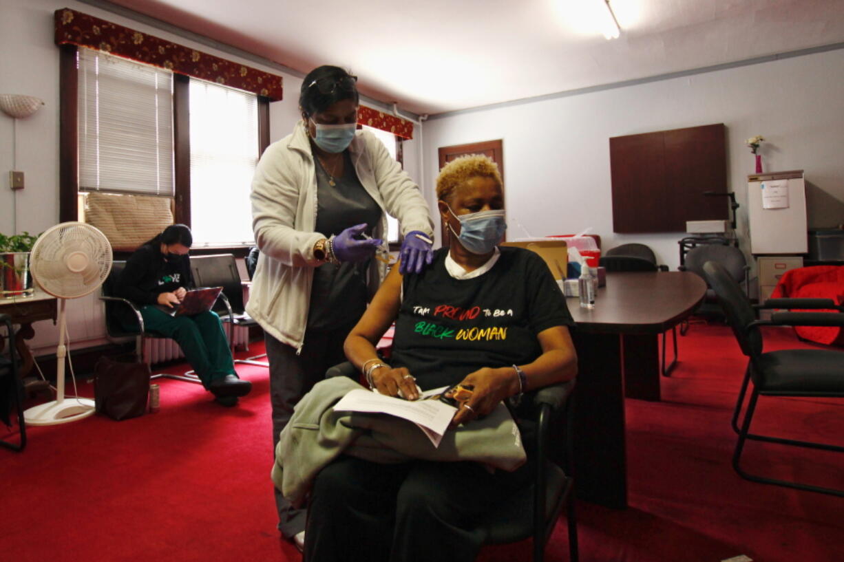 In this photo taken May 5, 2021, Melanie Paige closes her eyes as she gets her first COVID-19 vaccination at her church, St. Matthew Christian Methodist Episcopal, in Milwaukee. It's one of the churches that was part of an effort with Pastors United, Milwaukee Inner City Congregations Allied for Hope, Souls to the Polls and the local health clinic Health Connections to get people vaccinated directly in churches.