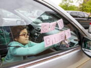 FILE - In this May 5, 2020, file photo, Elizabeth Ruiz, 7, puts up post-it notes on her mother's car window that spell out "God Bless U" as she and her mother Daylin Lemus, of Adelphi, Md., wait in a line of hundreds of cars to receive a Catholic Charities distribution of food at Northwestern High School, in Hyattsville, Md. The Department of Agriculture is sending $1 billion to the country's food bank networks, seeking to expand the reach of the system and revamp the way food banks acquire and distribute aid.