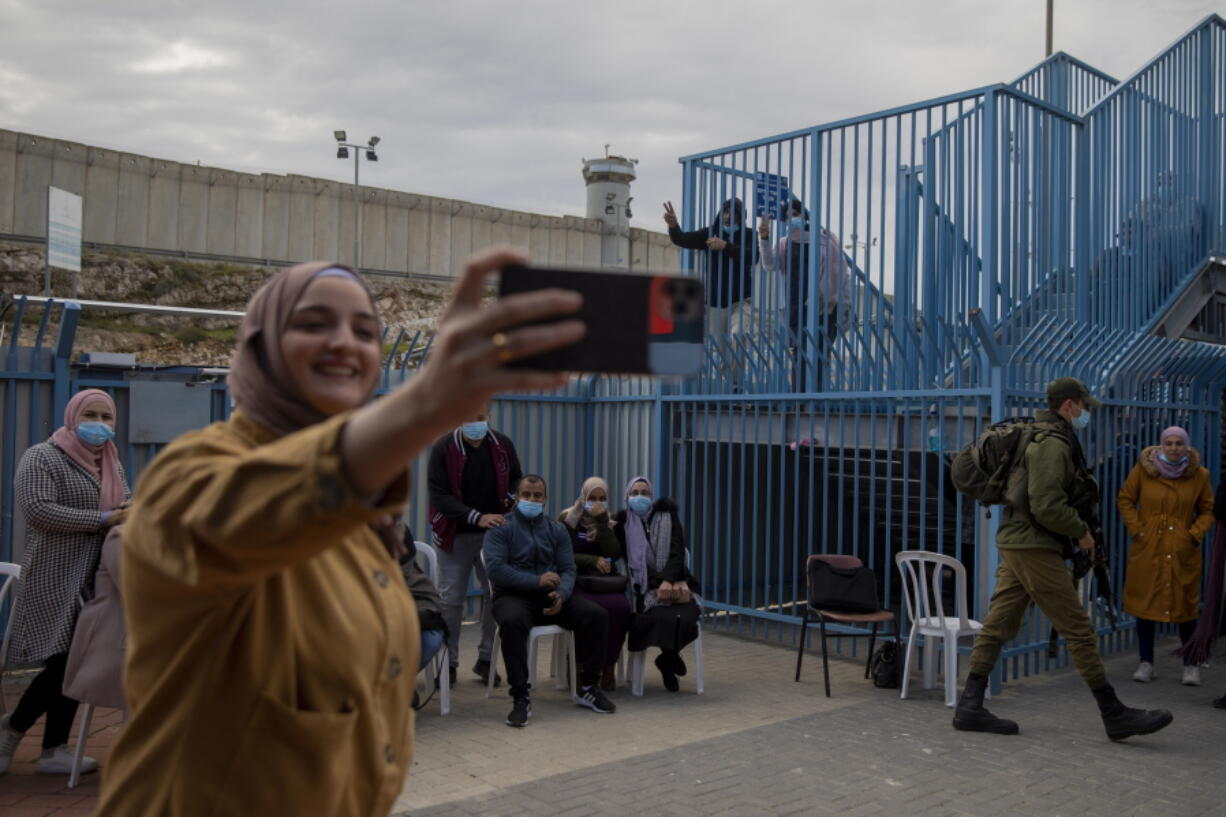 FILE - In this Feb. 23, 2021, file photo, Palestinians take a selfie after receiving the coronavirus vaccine from an Israeli medical team at the Qalandia checkpoint between the West Bank city of Ramallah and Jerusalem. Israel said Friday, June 18, 2021 it will transfer around 1 million doses of soon-to-expire coronavirus vaccines to the Palestinian Authority in exchange for a similar number of doses the Palestinians expect to receive later this year.