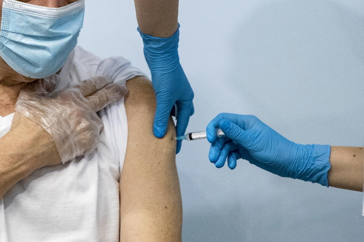 FILE - In this Jan. 20, 2021, file photo, a Russian medical worker, right, administers a shot of Russia's Sputnik V coronavirus vaccine to a patient in a vaccination center in Moscow, Russia. Authorities in four Russian regions this week made COVID-19 vaccinations mandatory for those working in certain sectors of the economy in a bid to boost Russia's slow immunization rates as coronavirus infections continue to soar. Moscow was the first to announce the measure on Wednesday, June 16, 2021 and the surrounding Moscow region, the Siberian region of Kemerovo and the far eastern Sakhalin promptly followed suit.