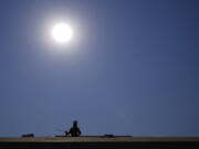 A roofer works on a new roof in a housing development while the sun beats down on him as the heat wave continues Thursday in Phoenix. (Ross D.