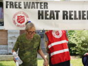 A pedestrian takes a bottle of water at a Salvation Army hydration station during a heatwave as temperatures hit 115-degrees, Tuesday, June 15, 2021, in Phoenix. (AP Photo/Ross D.