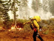 FILE - In this Sept. 14, 2020 file photo Cal Fire Battalion Chief Craig Newell carries a hose while battling the North Complex Fire in Plumas National Forest, Calif. U.S. wildfire managers are considering shifting from seasonal firefighting crews to full-time, year-round crews to deal with what has become a year-round wildfire season and to make wildland firefighting jobs more attractive by increasing pay and benefits. U.S. Forest Service Deputy Chief Christopher French, testifying before the U.S. Senate Committee on Energy and Natural Resources, said Thursday, June 24, 2021 agencies will seek to convert at least 1,000 seasonal wildland firefighters to permanent, full-time, year-round workers.