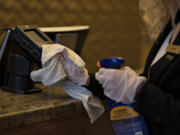 Guest service agent Libby Lusk keeps the credit card machines at the front desk disinfected at the Hilton Vancouver in 2020.