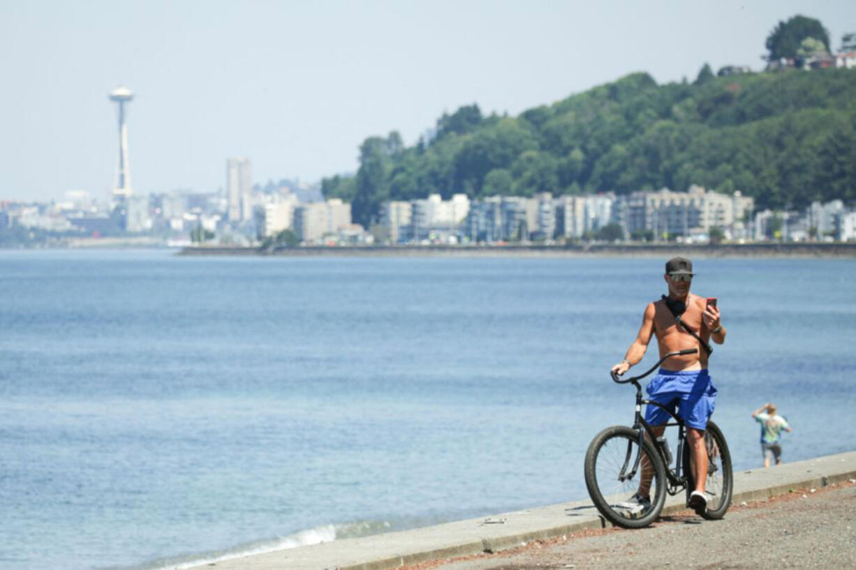 A bike rider checks his phone Tuesday in Seattle as an excessive heat warning remains in effect a day after record-breaking temperatures from an historic heat wave throughout the region.