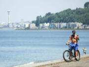 A bike rider checks his phone Tuesday in Seattle as an excessive heat warning remains in effect a day after record-breaking temperatures from an historic heat wave throughout the region.