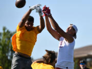 Players from Kelso and Sandy (Ore.) high school leap for a ball Saturday during the Rumble at the River 7-on-7 football tournament at Union High School.