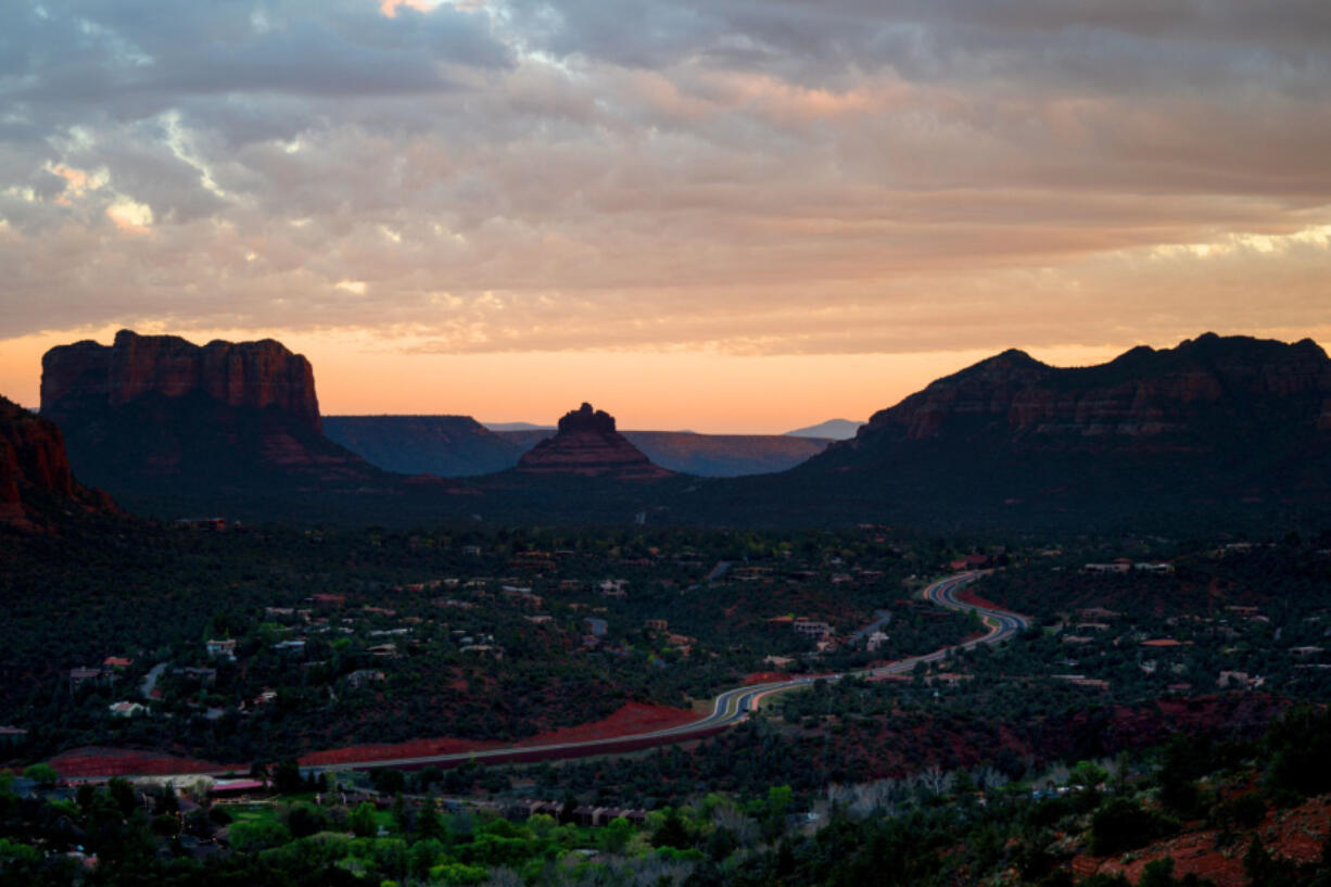 Overcast skies as the sun sets over the Verde Valley region, as people watch the sunset from atop of the summit of the Airport Mesa Loop Trail on Monday, April 20, 2020 in Sedona, Arizona.