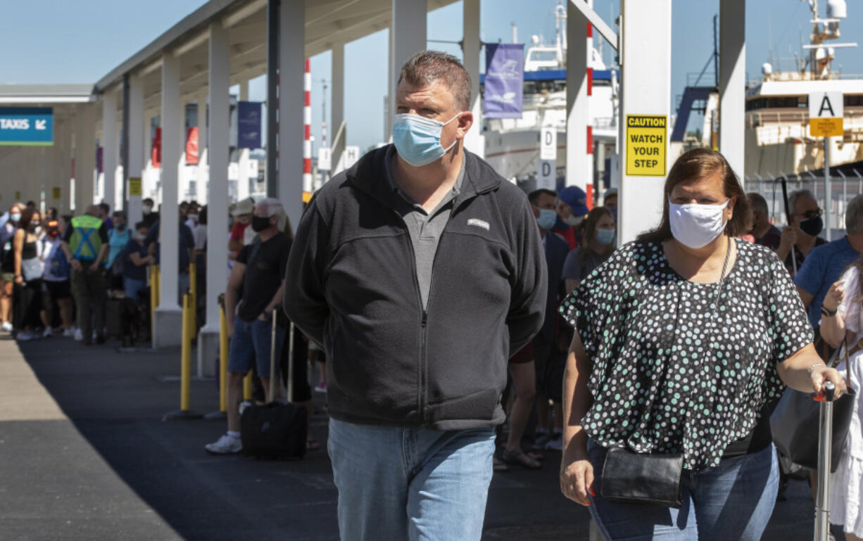 Peter and Kathy Dorney, from Massachussetts, make their way to the terminal where they will check in for their cruise to Alaska aboard the Serenade of the Seas at Terminal 91 in Seattle on July 19, 2021. (Ellen M.