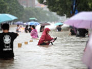 People walk in the flooded road after record downpours in Zhengzhou, in central China's Henan province, on July 20, 2021.