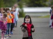 Kindergartner Tiffany Chang briefly drops her mask to enjoy a socially-distanced snack after recess at Eisenhower Elementary School in May. All students and staff will need to wear masks when the school year starts.