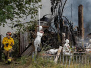 Captain Kenny Bjur of Clark-Cowlitz Fire Rescue lends a hand at the scene on Northeast 92nd Avenue in Battle Ground on Monday morning, July 5, 2021.