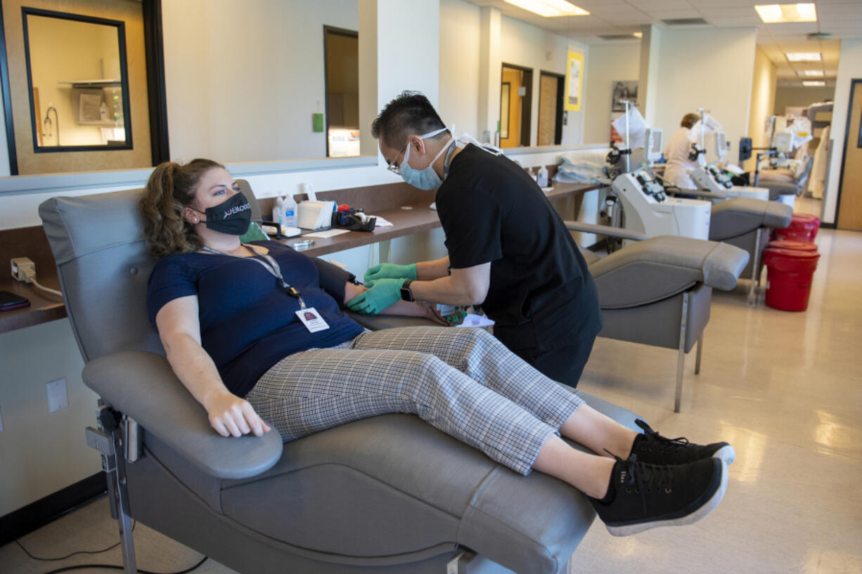 Lauren Reagan, center, the mother of the late Declan Reagan, chats with colleague Tin Nguyen as she donates blood at Bloodworks Northwest Vancouver Donor Center on June 25. Bloodworks and blood donations helped Declan live five months longer than expected. At top, Declan plays in his dad's police cruiser at the Washougal Police Department on Sept. 5, 2017.