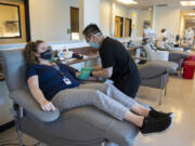 Lauren Reagan, center, the mother of the late Declan Reagan, chats with colleague Tin Nguyen as she donates blood at Bloodworks Northwest Vancouver Donor Center on June 25. Bloodworks and blood donations helped Declan live five months longer than expected. At top, Declan plays in his dad's police cruiser at the Washougal Police Department on Sept. 5, 2017.