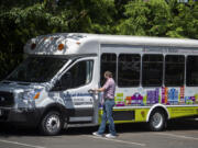 Michael Kelly, transportation services manager for Community in Motion, steps into one of two newly decorated vehicles Thursday afternoon.