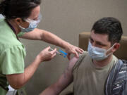 Veterans Affairs registered nurse Jennifer Graham gives Army veteran Nathan Gegenheiner the COVID-19 vaccine. Gegenheiner had to postpone his vaccination until he finished cancer treatment.