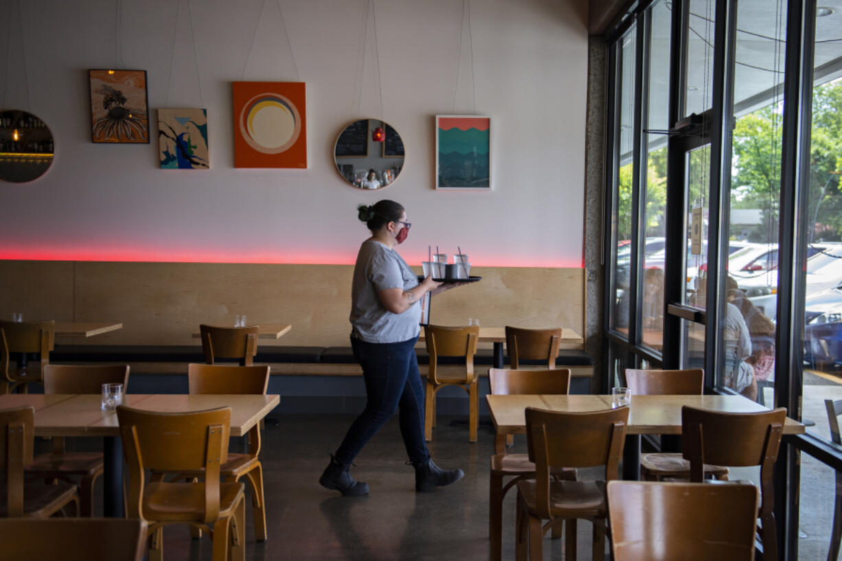 Server Bethany Fischer walks through the dining room at Rally Pizza that is now open for those wanting to eat inside, on Friday afternoon.