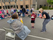 WASHOUGAL:  Columbia River Gorge Elementary School first-grader Jase Kenyon gets ready to smash Principal Tracey MacLachlan as teacher Jessica Warta observed.