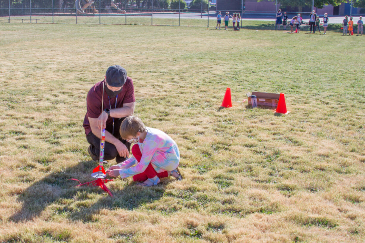 WOODLAND: Brian Peterson, third-grade teacher, helps a student prepare a rocket for launch.