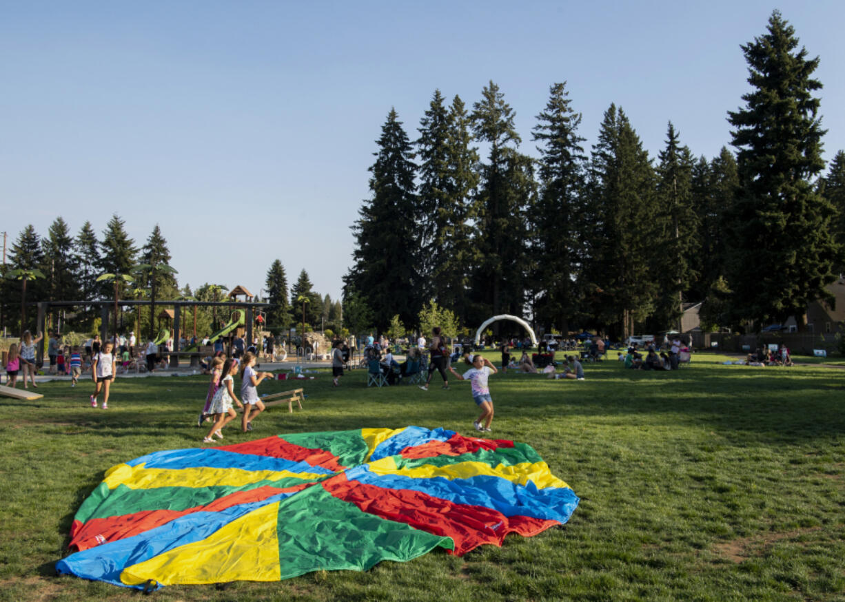 At right, kids run through a field Thursd ay at a park in Vancouver's North Image neighborhood. The new park at Northeast 52nd Street and 137th Avenue hosted Party in the Parks, which featured live music, games and informative booths.